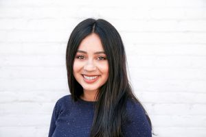 Smiling young female with black hair parted in the middle