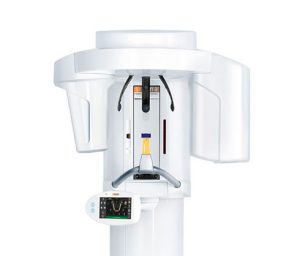 White panoramic dental x ray machine designed for patient to sit in, includes screen featuring dental radiograph