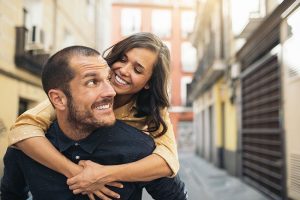 young couple on vacation walking down a street smiling