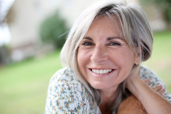 older woman smiling while sitting outside on grass