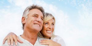 happy older couple hugging underneath a bright blue sky