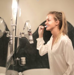 young woman brushing her teeth, practicing proper oral hygiene